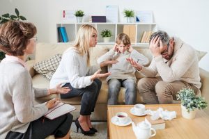 Sad son covering ears while parents having quarrel at therapy se