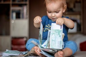 Inspired toddler boy holds hundred Euro denominations