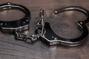 Handcuffs And Keys On Brown Wooden Table Background