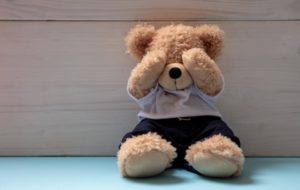 Teddy bear in an empty child room, covering eyes