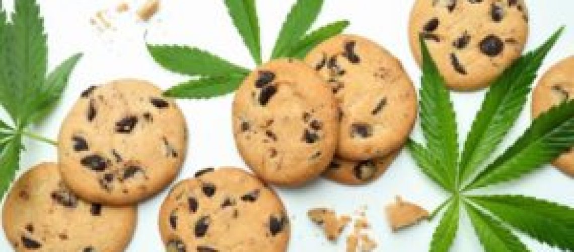 Cannabis leaves and cookies on white background