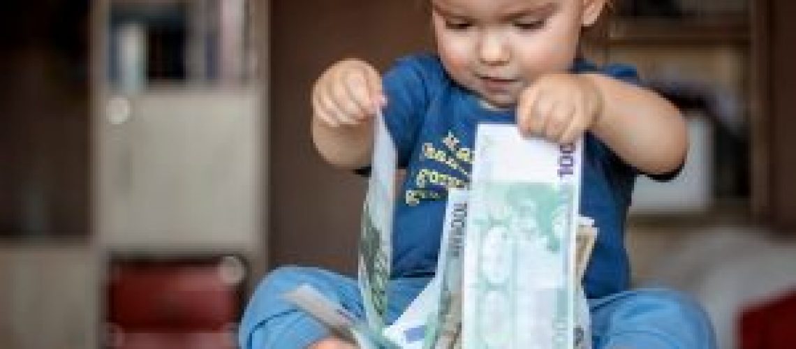 Inspired toddler boy holds hundred Euro denominations