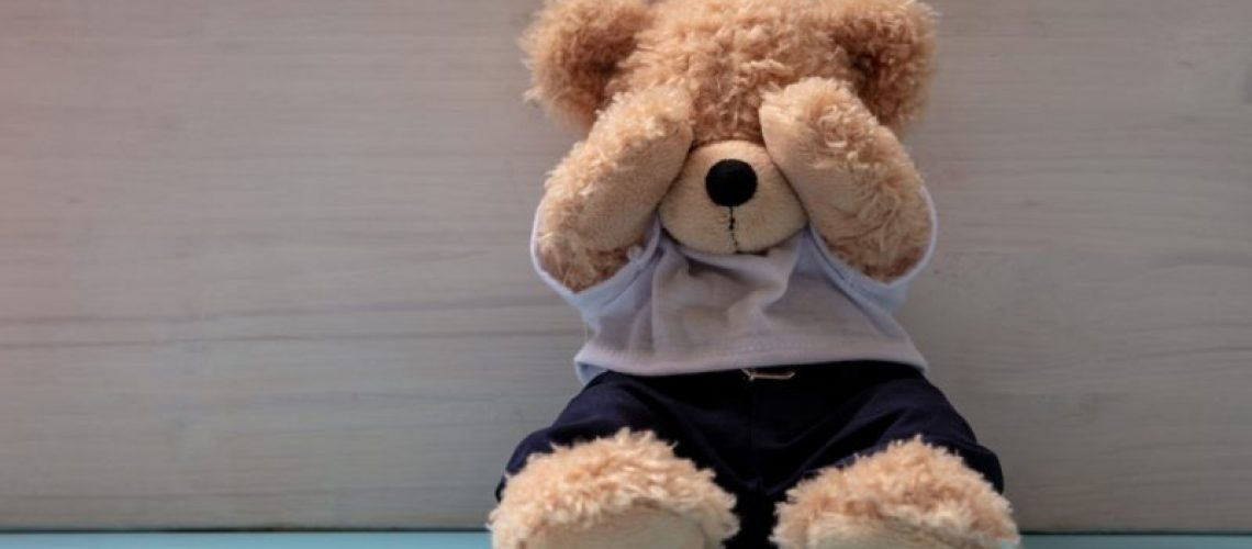 Teddy bear in an empty child room, covering eyes